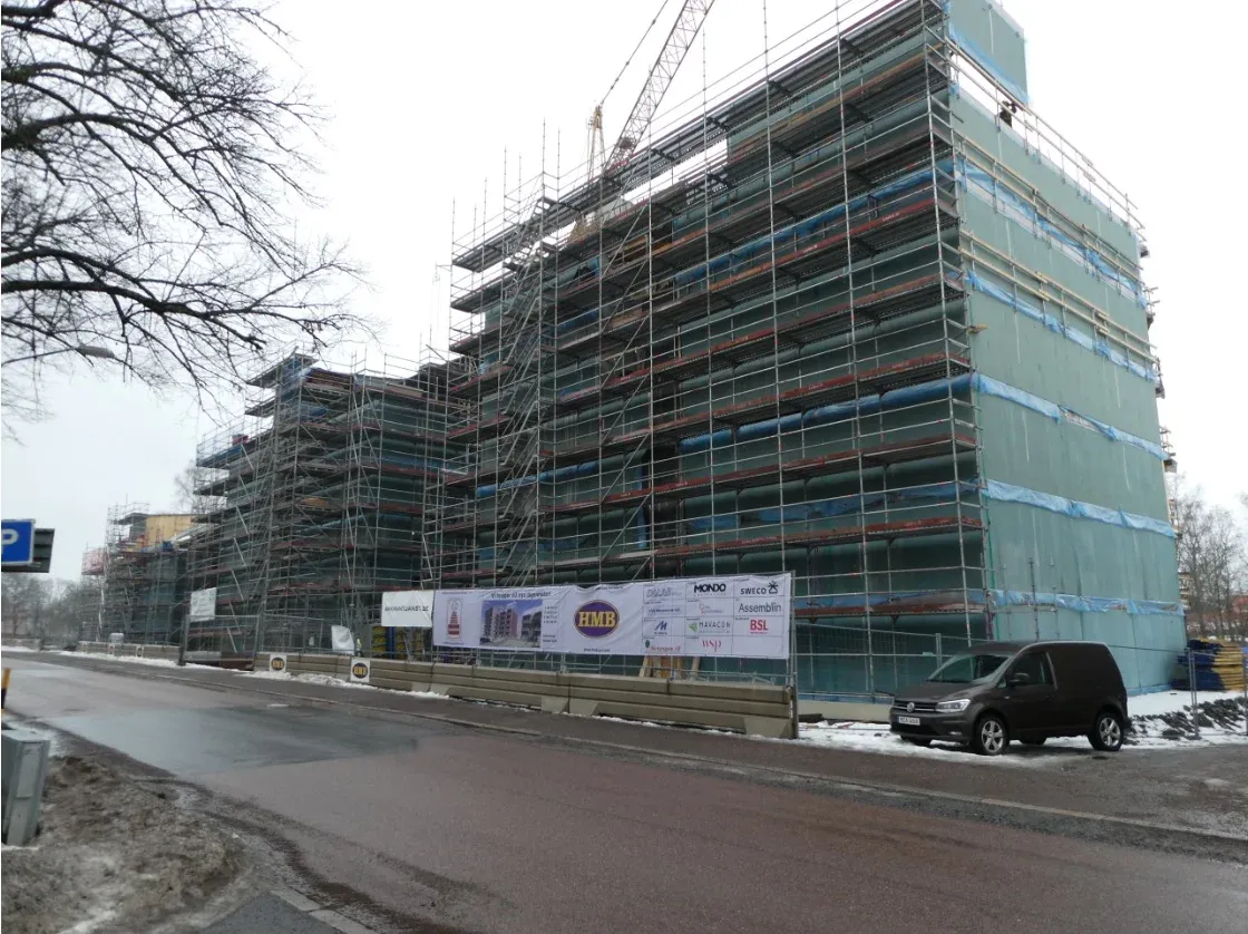 Flerbostadshus helt inklätt i byggnadsställning.