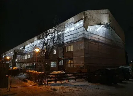 Byggnaden nattetid, upplyst inifrån genom väderskyddsväven.