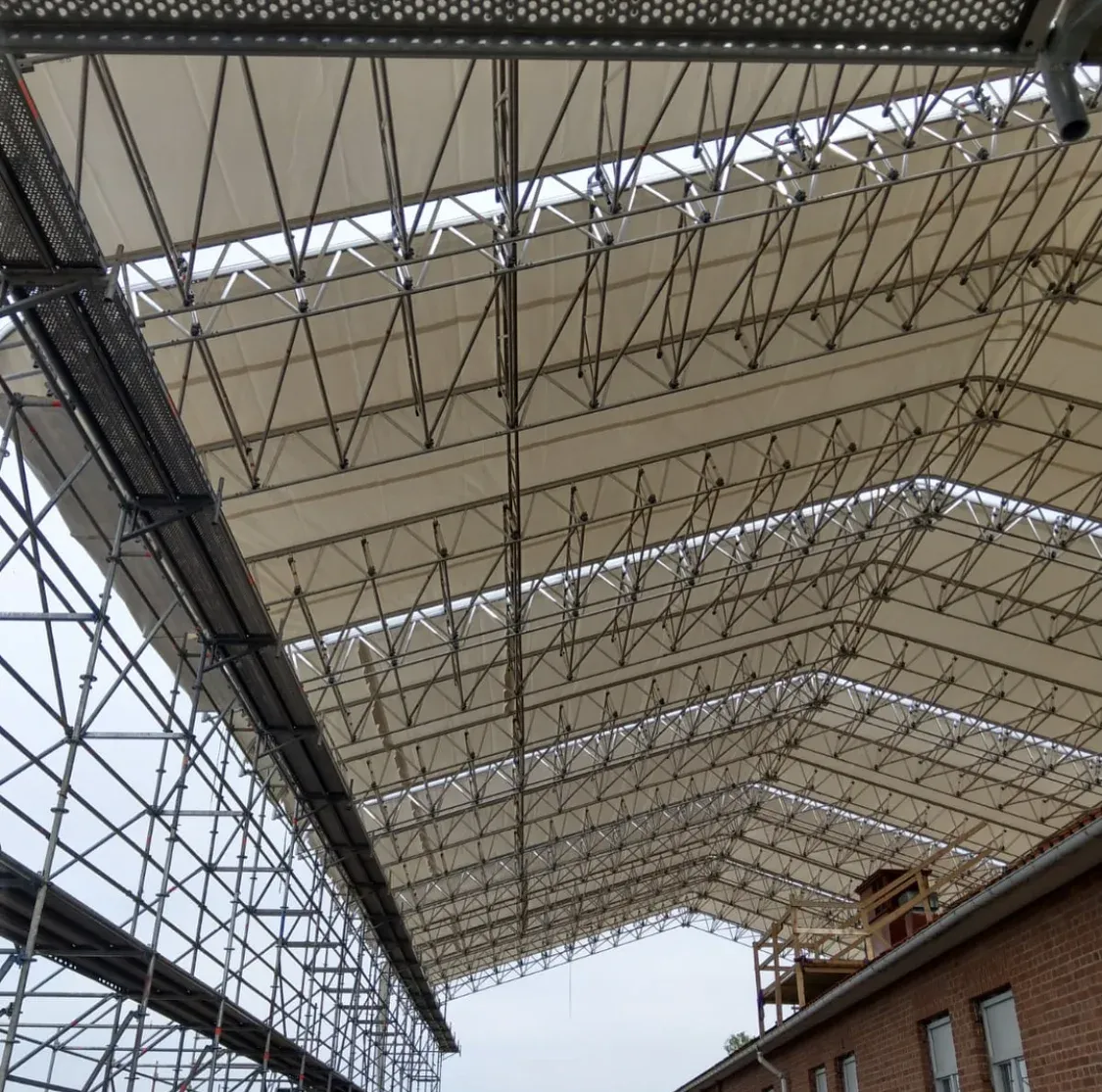 Väderskydd av armerad plast spänt över en byggnadsställning.